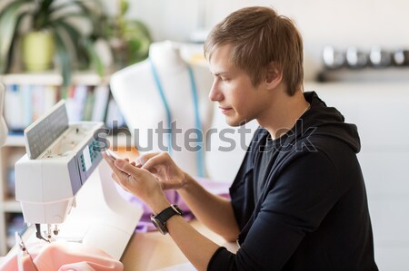 fashion designer with smartphone working at studio Stock photo © dolgachov