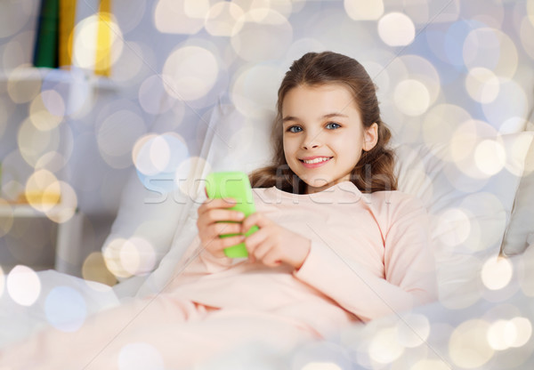 Ragazza felice letto smartphone home persone bambini Foto d'archivio © dolgachov