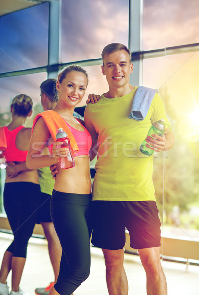 Stock photo: smiling couple with water bottles in gym