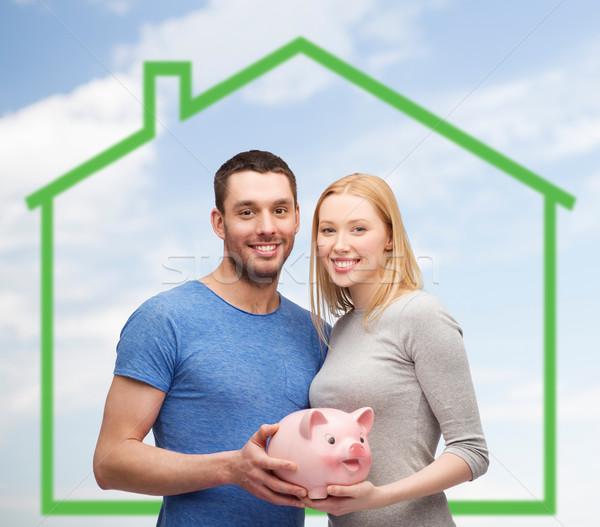 smiling couple holding piggy bank over green house Stock photo © dolgachov