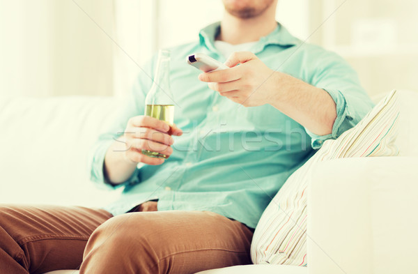 man with beer and remote control at home Stock photo © dolgachov