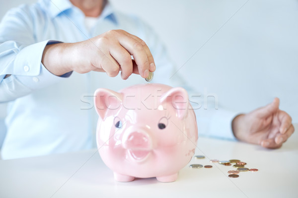 close up of old man putting coins into piggybank Stock photo © dolgachov