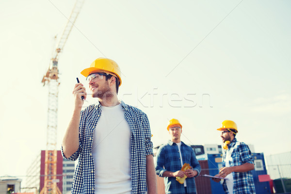 Stock photo: group of smiling builders in hardhats with radio