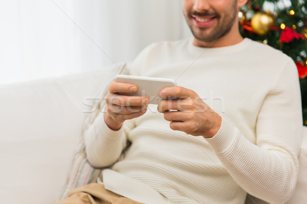 smiling man with smartphone at home for christmas Stock photo © dolgachov