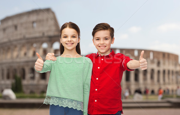 Stock photo: happy boy and girl showing thumbs up over coliseum