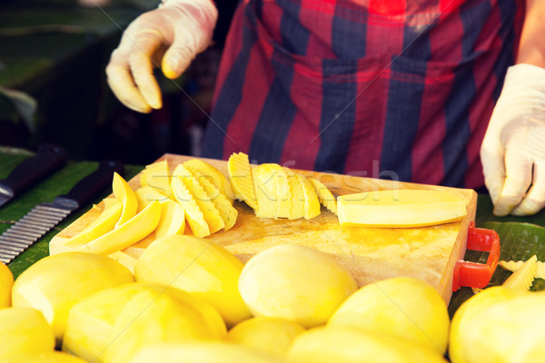close up of cook hands and mango at street market Stock photo © dolgachov