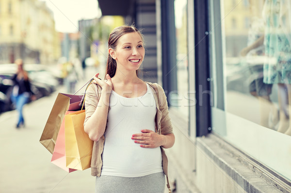 happy pregnant woman with shopping bags at city Stock photo © dolgachov