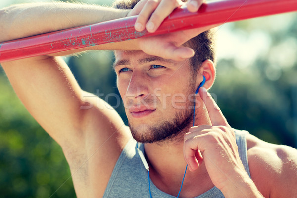 young man with earphones and horizontal bar Stock photo © dolgachov