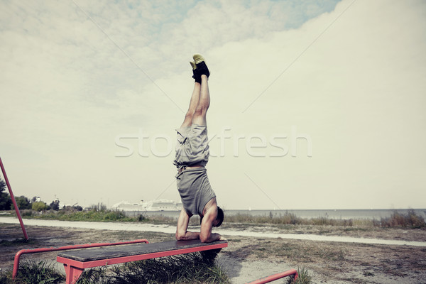 young man exercising on bench outdoors Stock photo © dolgachov