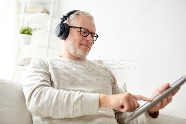 senior man with tablet pc and headphones at home Stock photo © dolgachov