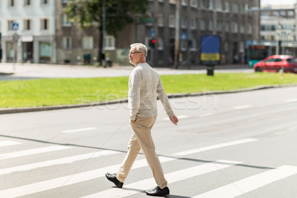 senior man walking along city crosswalk Stock photo © dolgachov