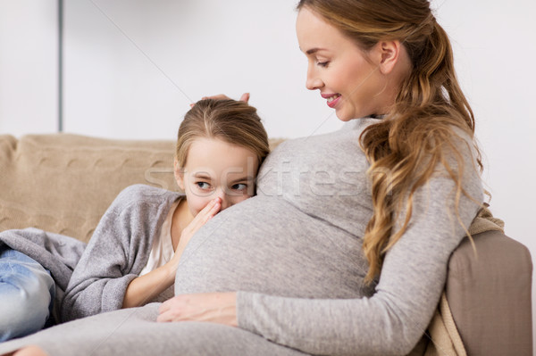 Stock photo: pregnant woman and girl talking to baby in belly