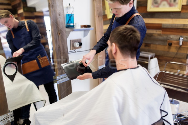 barber showing tablet pc to man at barbershop Stock photo © dolgachov