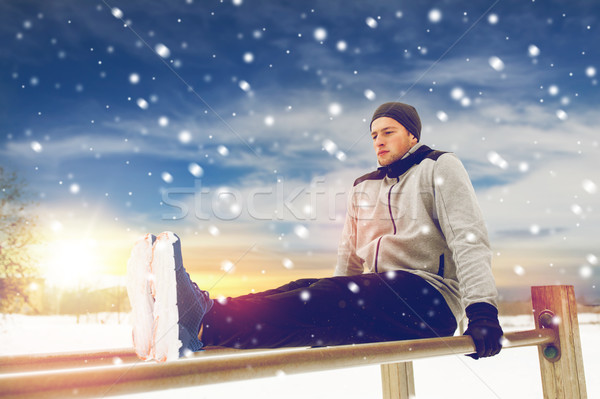 young man exercising on parallel bars in winter Stock photo © dolgachov