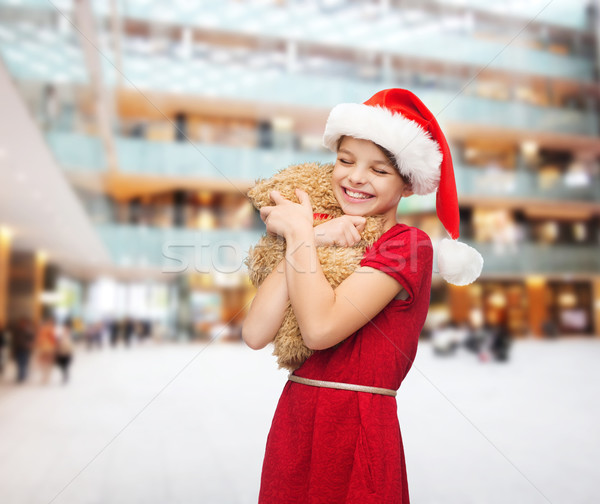 Stock photo: smiling girl in santa helper hat with teddy bear