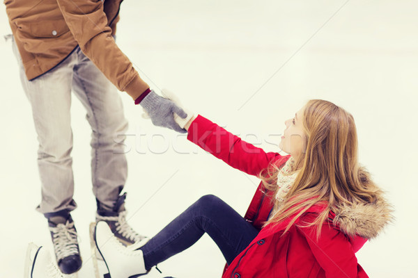 Stock photo: man helping women to rise up on skating rink