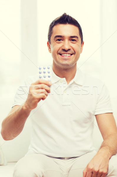 happy man showing pack of pills at home Stock photo © dolgachov