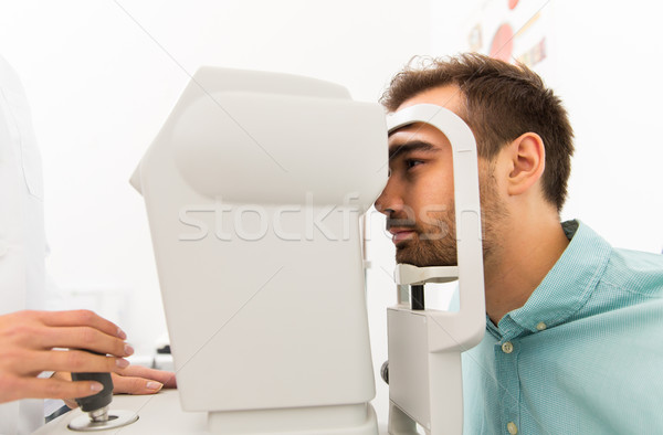 optician with autorefractor and patient at clinic Stock photo © dolgachov