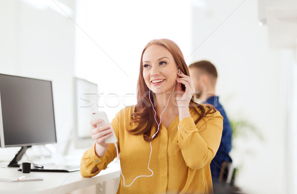 woman with earphones and smartphone at office Stock photo © dolgachov