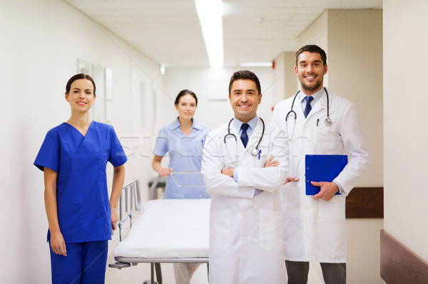 Stock photo: group of happy doctors with gurney at hospital