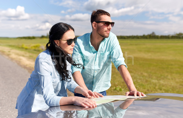 happy man and woman with road map on car hood Stock photo © dolgachov