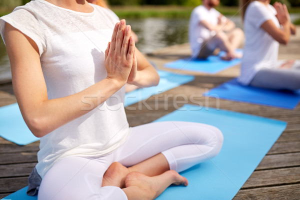 close up of people making yoga exercises outdoors Stock photo © dolgachov