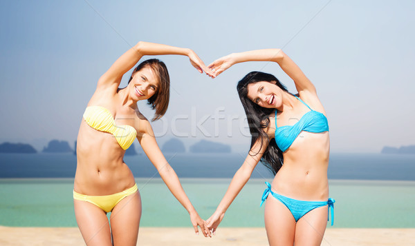 happy women making heart shape on summer beach Stock photo © dolgachov