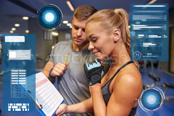 smiling woman with trainer and clipboard in gym Stock photo © dolgachov