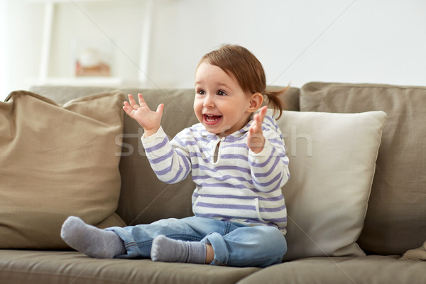 Stock photo: happy smiling baby girl sitting on sofa at home