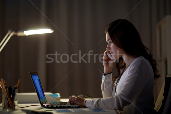 woman with laptop calling on smartphone at office Stock photo © dolgachov