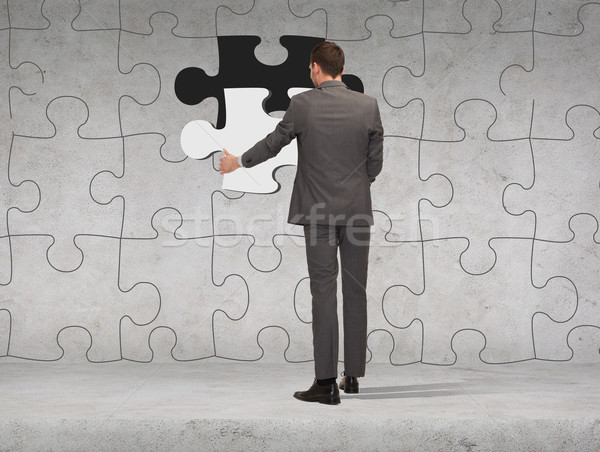businessman in suit setting piece of puzzle Stock photo © dolgachov