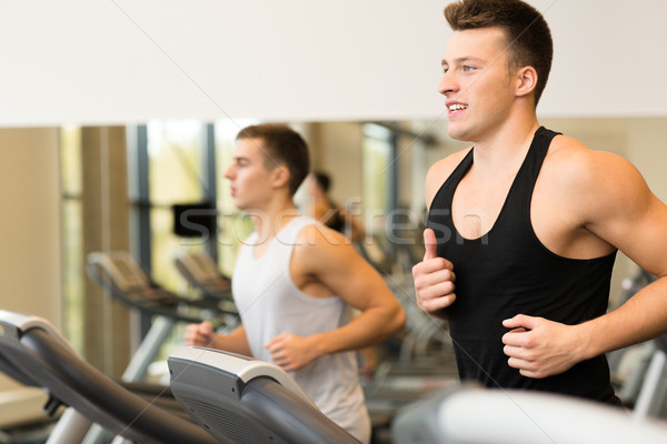 Stock photo: smiling men exercising on treadmill in gym