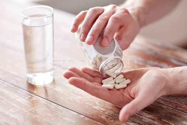 Közelkép férfi áramló tabletták bögre kéz Stock fotó © dolgachov