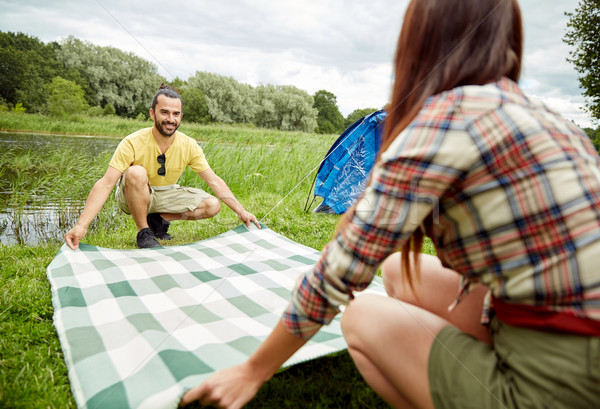 happy couple laying picnic blanket at campsite Stock photo © dolgachov