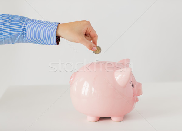 close up of hand putting coin into piggy bank Stock photo © dolgachov
