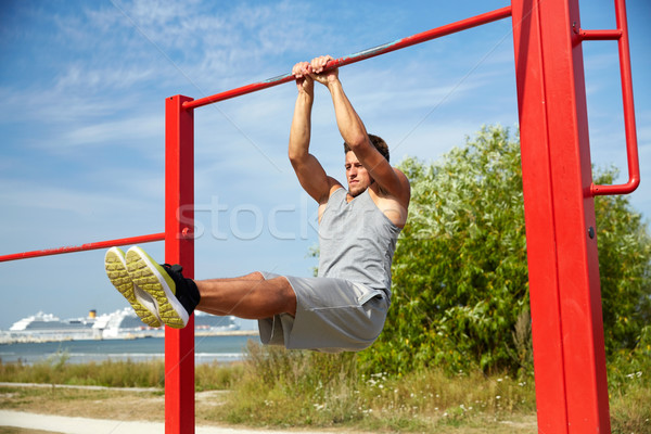 Stock photo: young man exercising on horizontal bar outdoors