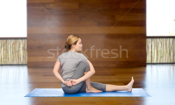 woman making yoga in twist pose on mat Stock photo © dolgachov