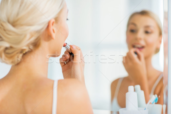 woman with lipstick applying make up at bathroom Stock photo © dolgachov