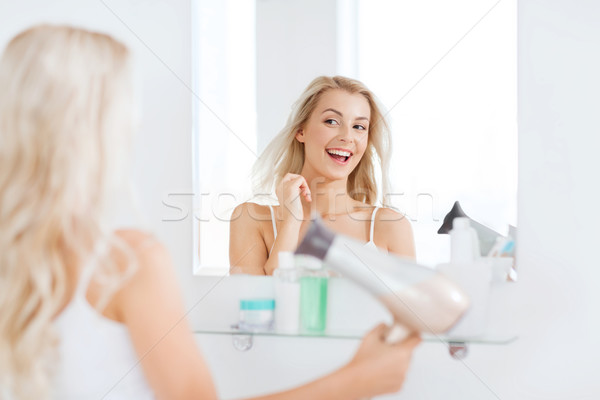happy young woman with fan drying hair at bathroom Stock photo © dolgachov
