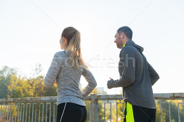 happy couple with earphones running outdoors Stock photo © dolgachov