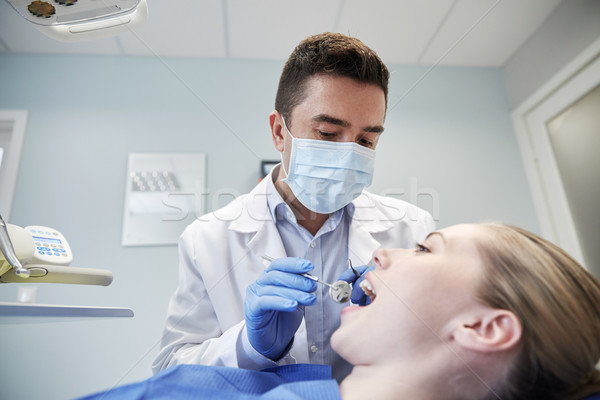 male dentist in mask checking female patient teeth Stock photo © dolgachov