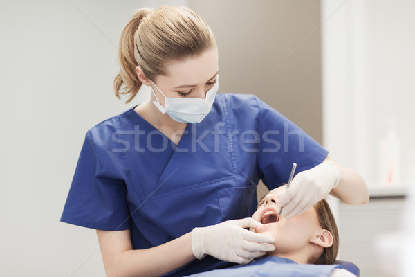 female dentist checking patient girl teeth Stock photo © dolgachov
