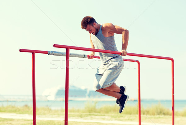 young man exercising on parallel bars outdoors Stock photo © dolgachov