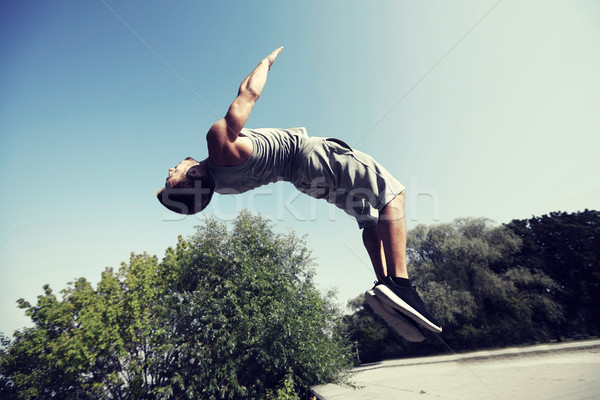 sporty young man jumping in summer park Stock photo © dolgachov