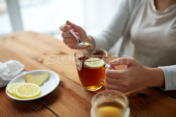 close up of woman adding honey to tea with lemon Stock photo © dolgachov
