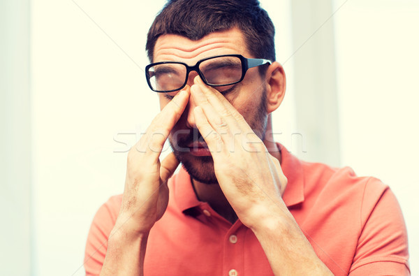 tired man in eyeglasses rubbing eyes at home Stock photo © dolgachov