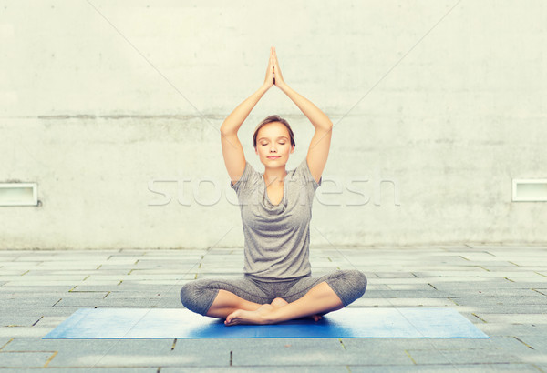 woman making yoga meditation in lotus pose on mat Stock photo © dolgachov