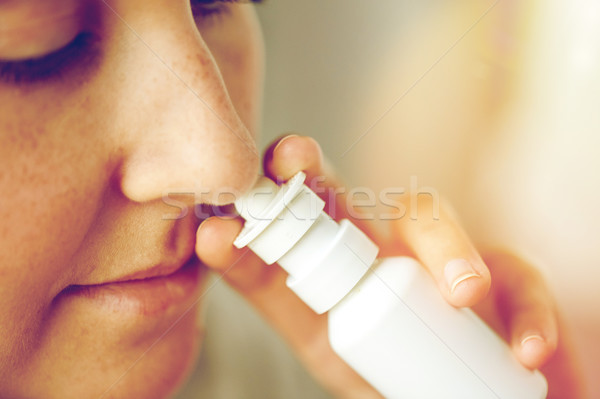 Stock photo: close up of sick woman using nasal spray