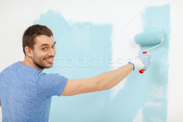 Stock photo: smiling man painting wall at home