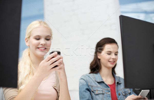 two teens with smartphones in computer class Stock photo © dolgachov